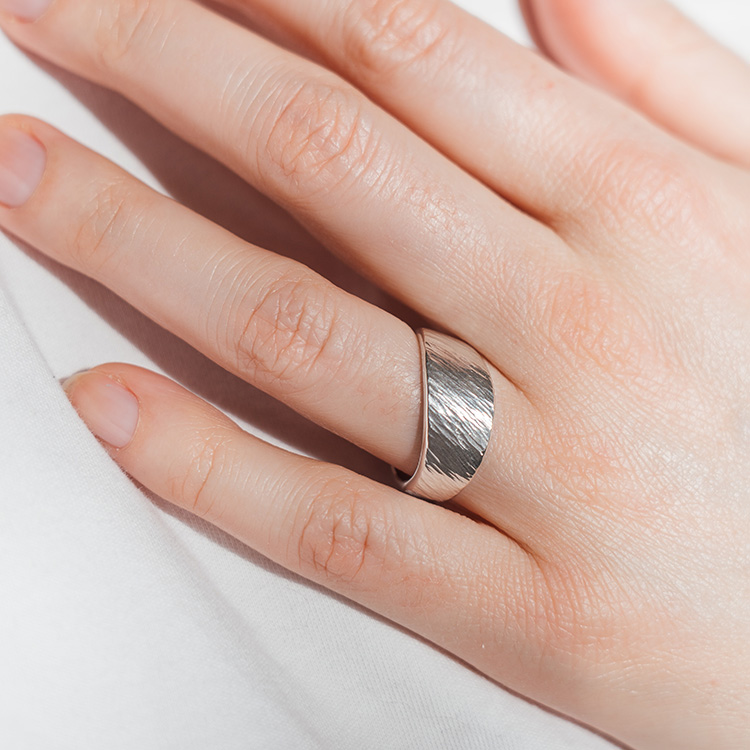 Ein Silberring mit gehämmerter Oberfläche am Finger getragen