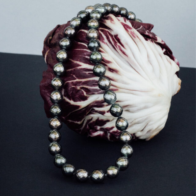 Perlenkette mit dunklen Perlen auf einem Radiccio