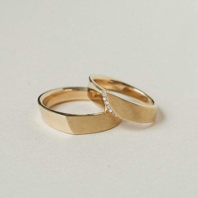 Trauringe aus Gelbgold in einer außergewöhnlichen Form. Teilweise poliert, teilweise matt. Im Damenring 7 Brillanten