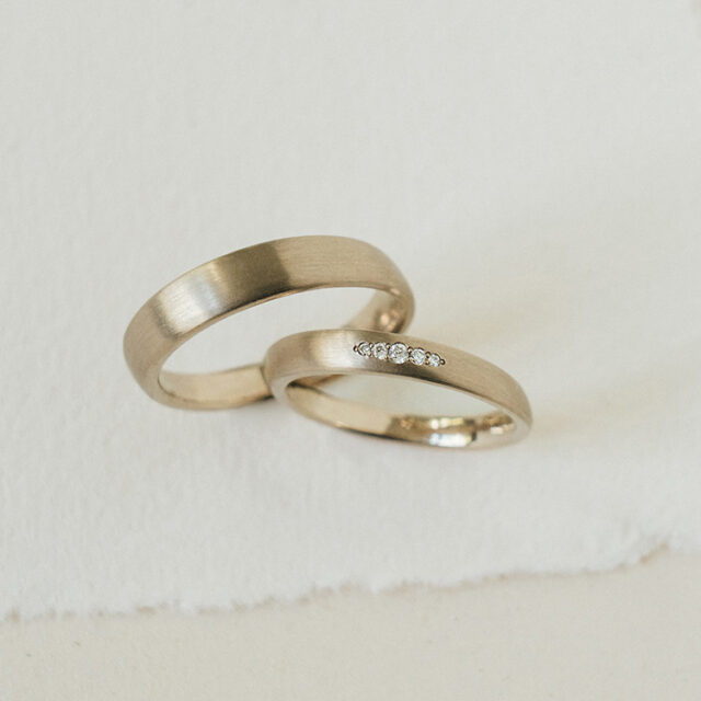 Klassische Trauringe aus einer warmen Weißgoldlegierung. Der Damenring mit fünf Brillanten in der Mitte