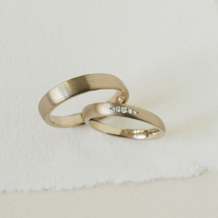 Klassische Trauringe aus einer warmen Weißgoldlegierung. Der Damenring mit fünf Brillanten in der Mitte