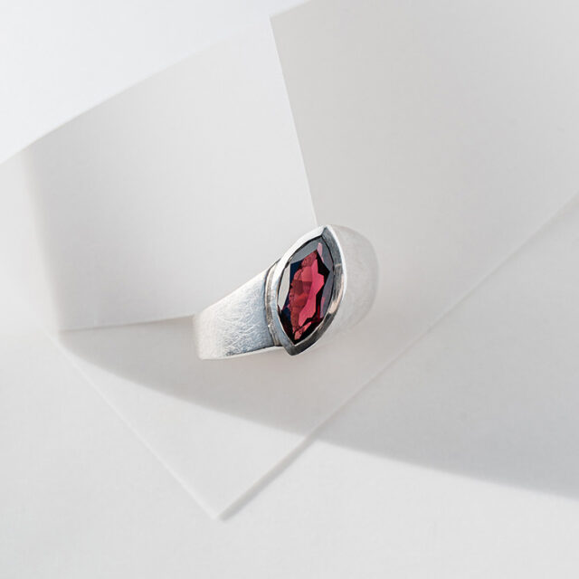 Ergonomischer Ring aus Silber mit matt strukturierter Oberfläche und großem dunkelroten Granat im Navette Schliff