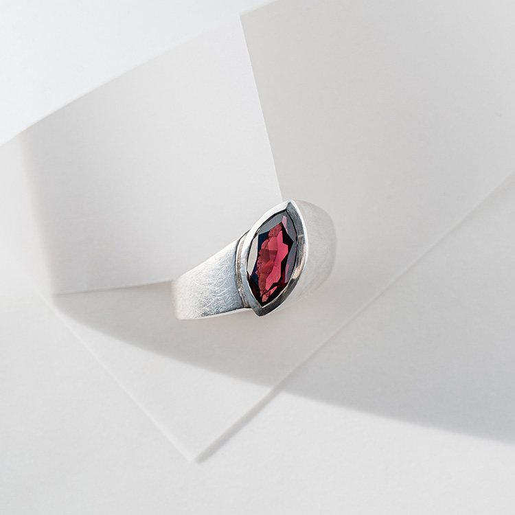 Ergonomischer Ring aus Silber mit matt strukturierter Oberfläche und großem dunkelroten Granat im Navette Schliff
