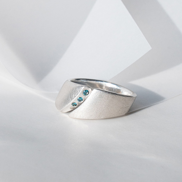 Ergonomischer Ring aus Silber mit besonderer Form und Spalt. Besetzt mit drei blauen Steinen