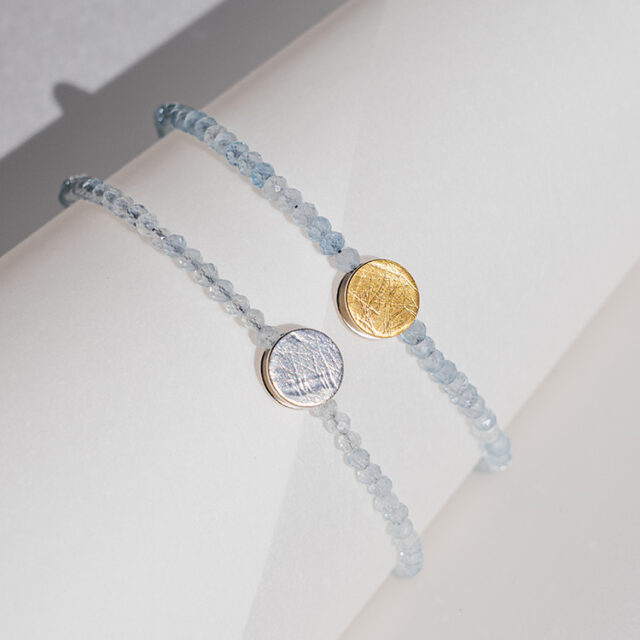 Armbänder mit hellblauen Aquamarin Steinen und Element aus Gold und Silber mit strukturierter Oberfläche.