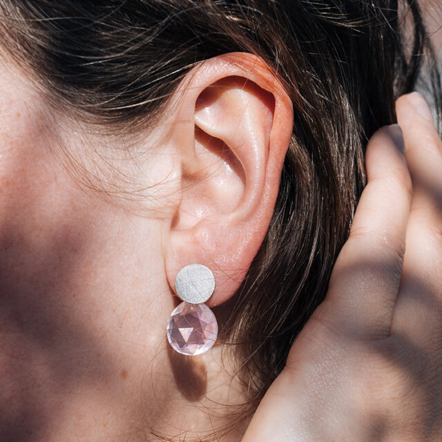 Ohrstecker mit Element aus Silber und Anhänger aus Rosenquarz am Ohr getragen