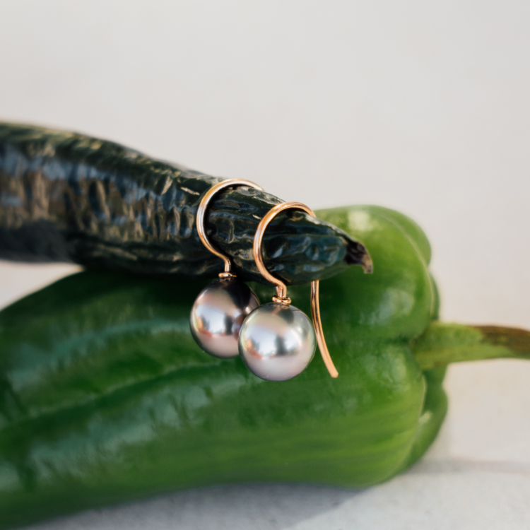 Ohrhänger mit dunkeln Perlen und Rotgold auf Paprika fotografiert