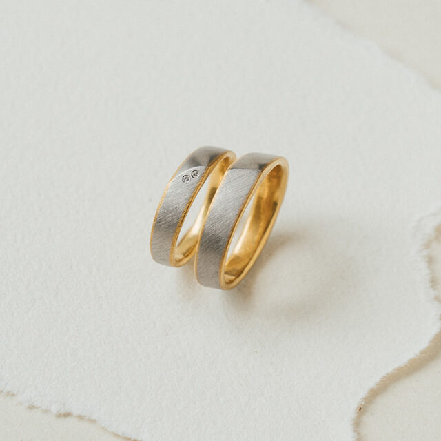 Besonderes Trauringpaar - bicolor, innen Gelbgold, außen in Platin gefertigt. Im Damenring Brillanten.