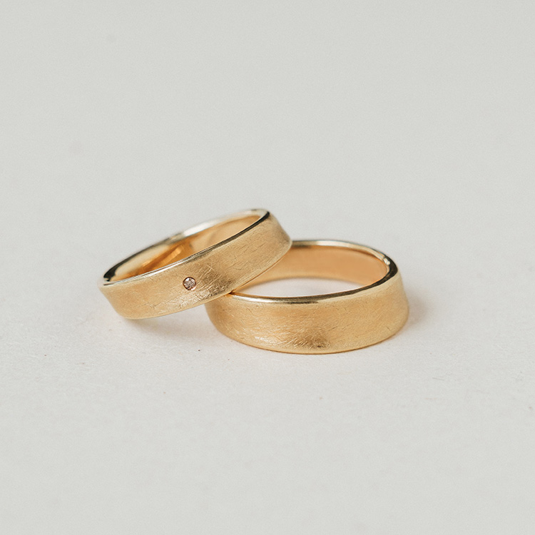 Eheringpaar Konkav aus Gelbgold mit kreismatter Oberfläche und Brillant im Damenring.