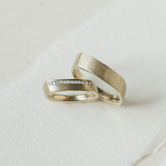 Trauringpaar aus Cremegold mit Kanten, der Damenring besetzt mit Brillanten