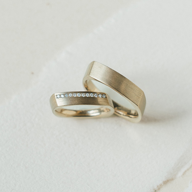 Trauringpaar aus Cremegold mit Kanten, der Damenring besetzt mit Brillanten