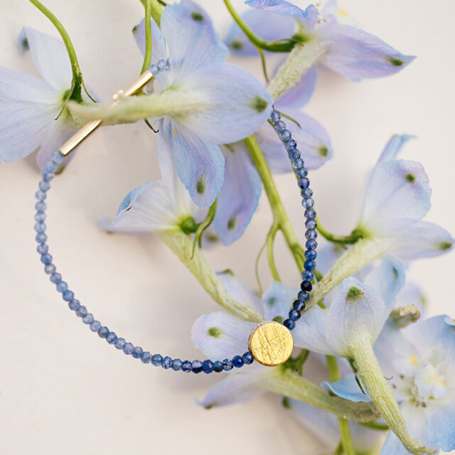 Armband mit blauem Saphir im Farbverlauf mit rundem Punkt-Element in gold in der Mitte.