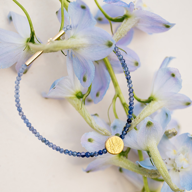 Armband mit blauem Saphir im Farbverlauf mit rundem Punkt-Element in gold in der Mitte.
