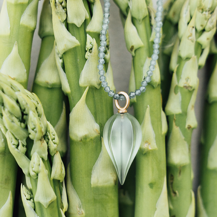 Kette mit grünen Steinen mit Anhänger aus Roségold und einem Prasiolith liegt auf grünem Spargel