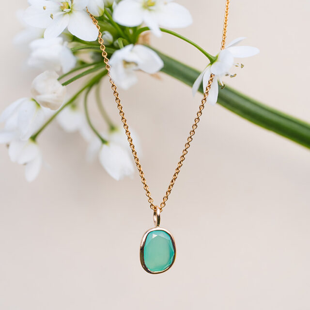 Kette aus Gold mit Anhänger mit einem Stein in leuchtend Grün / Türkis.