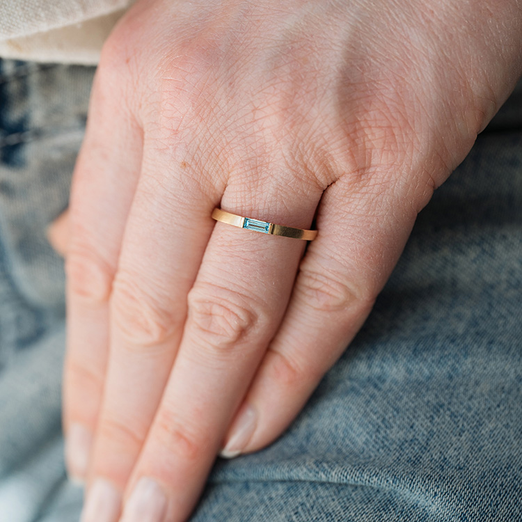 Schmaler Bandring in gold mit hellblauem Diamant im Baguette Schliff