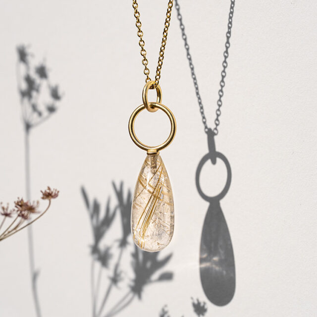 Anhänger mit goldenem Kreis und Rutilquarz mit goldenen Nadeln an einer feinen goldenen Kette