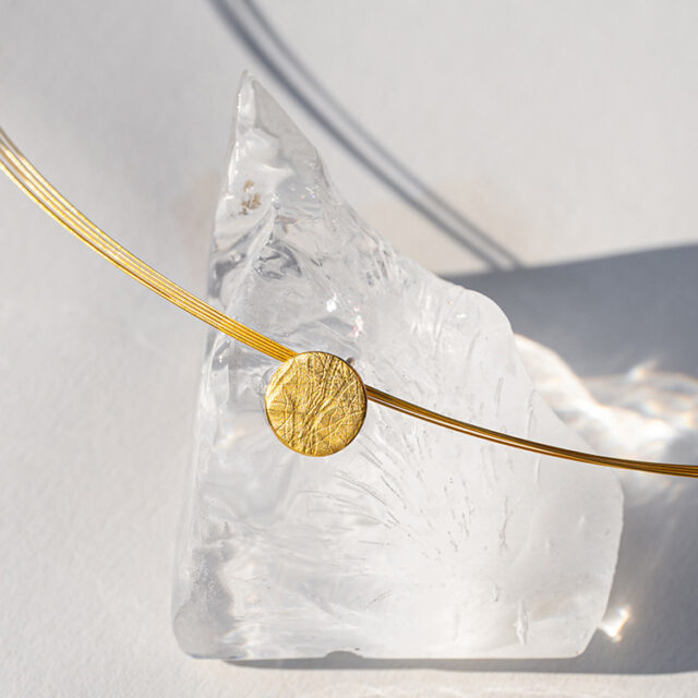 Kette mit Punkt Element aus Silber mit Gelbgold mit aufgewalzter Struktur.
