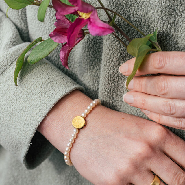 Perlenarmband mit Punkt Element in Silber mit Gold am Handgelenk.