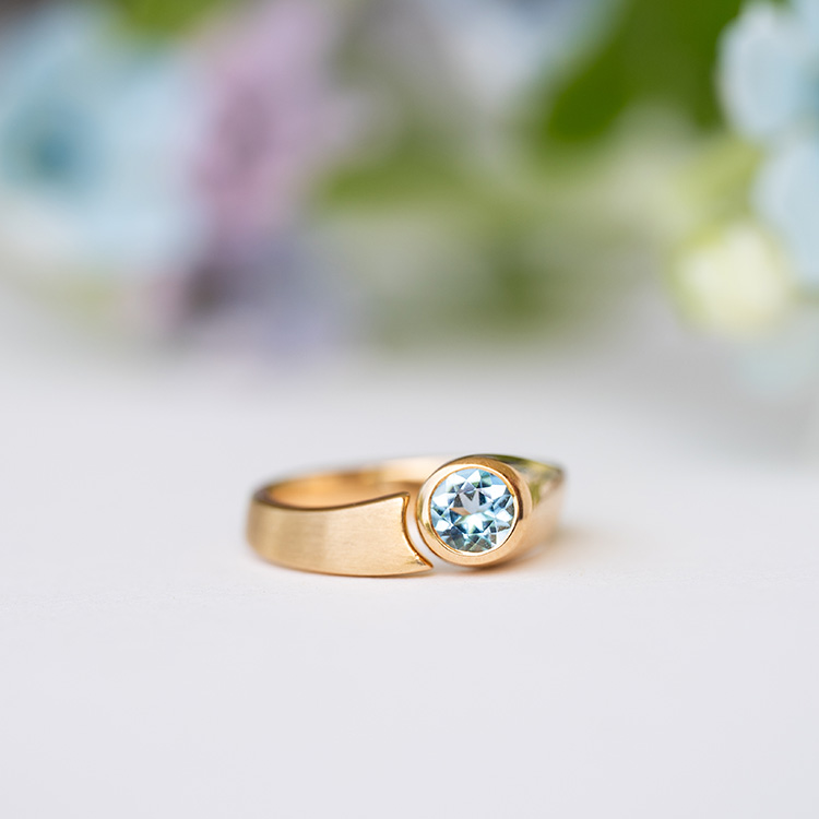 Ring mit Spalt aus Gelbgold mit matter Oberfläche und hellblauem Aquamarin