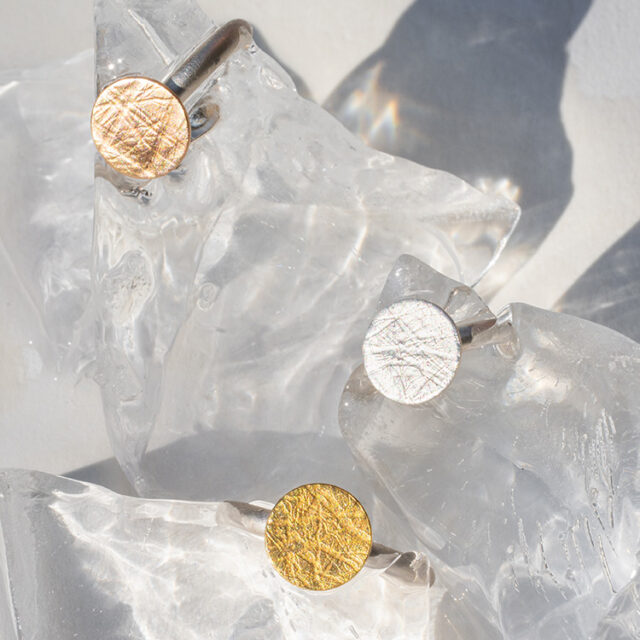 4 Ringe aus Silber mit Punkt Element mit aufgewalzter Struktur mit Gelbgold, Roségold und Silber.